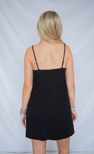 Person wearing a black slip dress against a plain background