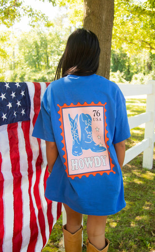 Person wearing a blue t-shirt with a graphic design in front of an American flag.