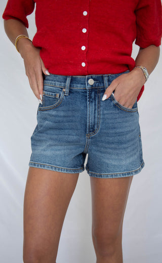 Women wearing dark wash high rise a line denim shorts. 