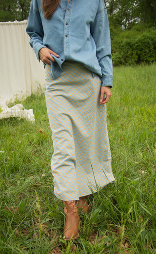 Person wearing a blue shirt and light-colored pants standing in a grassy area.