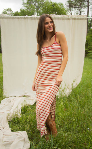 Woman in a striped dress standing in a grassy field with a white curtain in the background