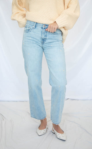 Person wearing light blue jeans and a yellow sweater on a plain background