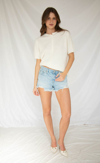 Women wearing light wash low rise denim shorts with fray cut off.  