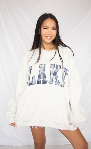 Woman wearing a white sweatshirt with 'LAKE' printed on it against a white background