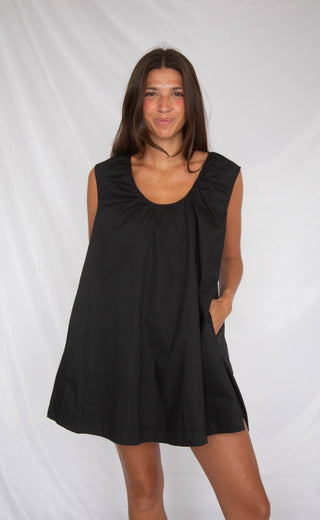 Woman wearing a black sleeveless dress against a white background