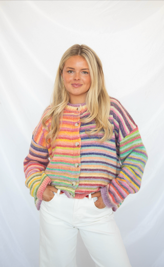 Woman wearing a colorful striped cardigan sweater against a white background