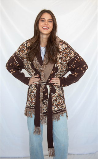 Woman wearing a patterned brown cardigan with a white background