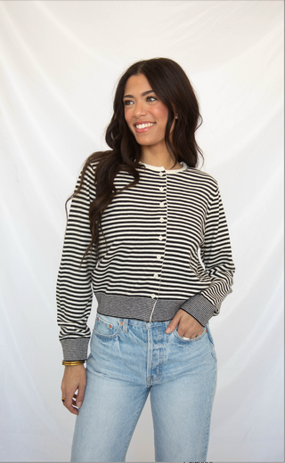 Woman wearing a black and white striped cardigan shirt and jeans against a white background