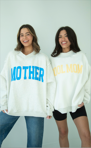 Two people wearing grey mock neck sweatshirts with 'MOTHER' and 'COOL MOM' text on a plain background