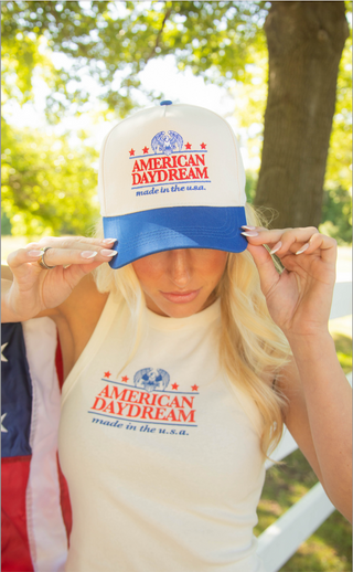 Person wearing a white cap and shirt with 'American Daydream' text, outdoors.
