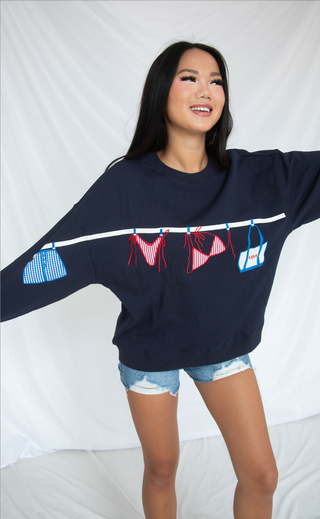 Woman wearing a navy blue sweatshirt with colorful graphic designs on a white background