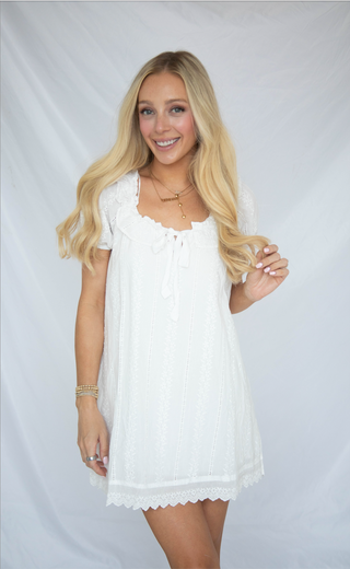Woman wearing a white dress against a plain background