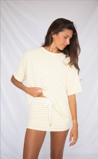 Woman wearing a white and yellow striped outfit on a plain background
